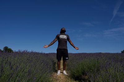 A man standing in front of the purple flower bed
